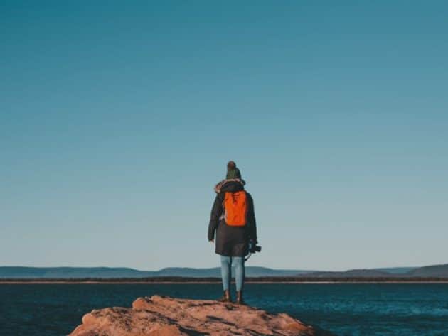 woman with red backpack looking out over water