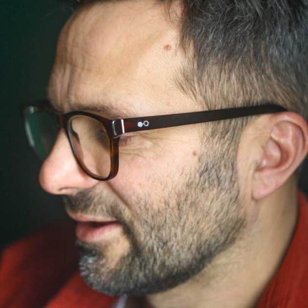 Man wearing blue light blocking glasses in a red brown square shape.