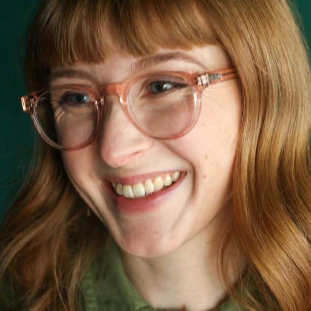 Woman wearing blue light blocking glasses in an oversized pink round shape.