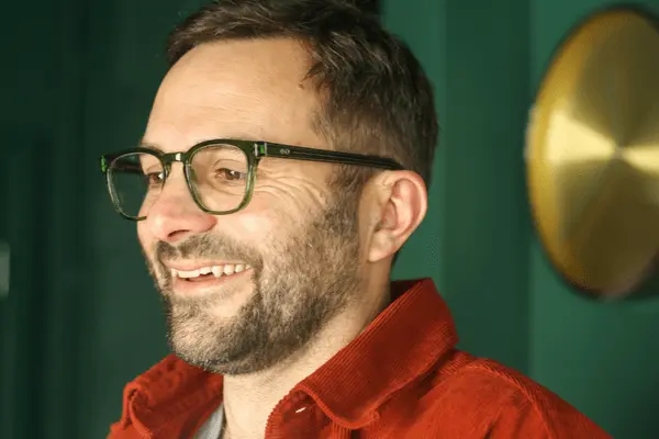 Stylish man in his 40's wearing emerald green sustainable blue light glasses in classic square frame.