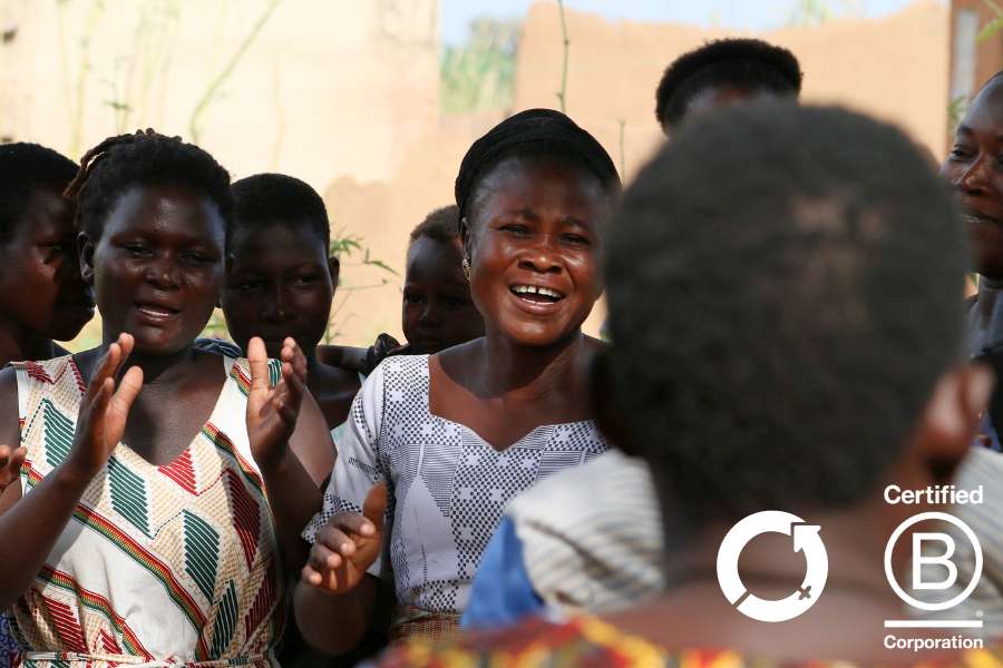 Supporting women in Ghana. Female artisan weavers smiling and clapping in village.