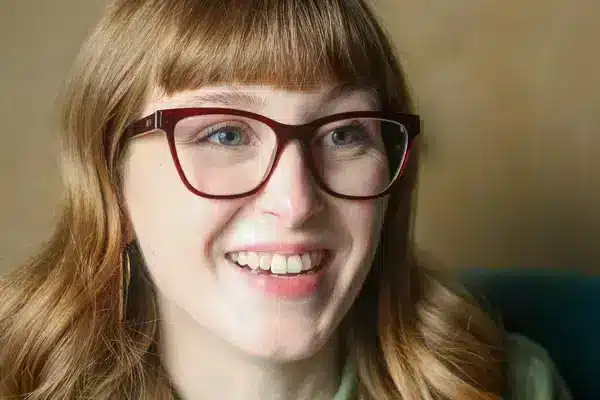 Woman wearing ruby red sustainable blue light glasses in square vintage cat eye shape.